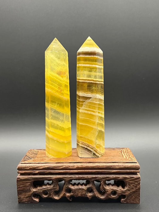 two yellow lined fluorite points on top of a carved wooden stand